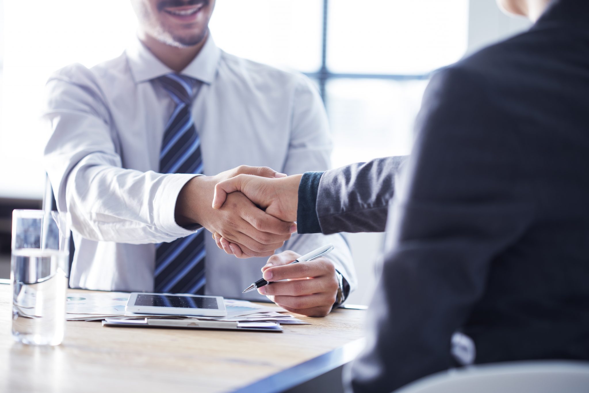 Two business people shaking hands at a table.