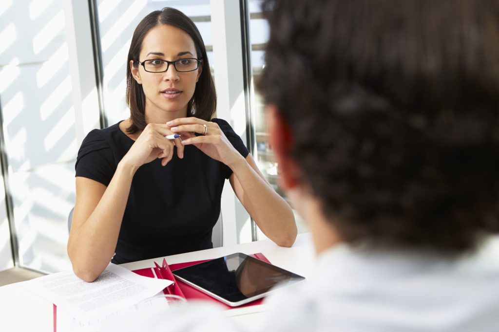 A woman is talking to a man in an office.