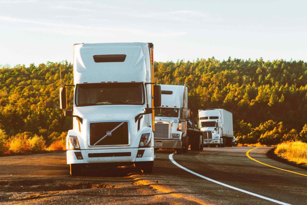 A convoy of semi trucks traveling along a road showcased in a collection page.